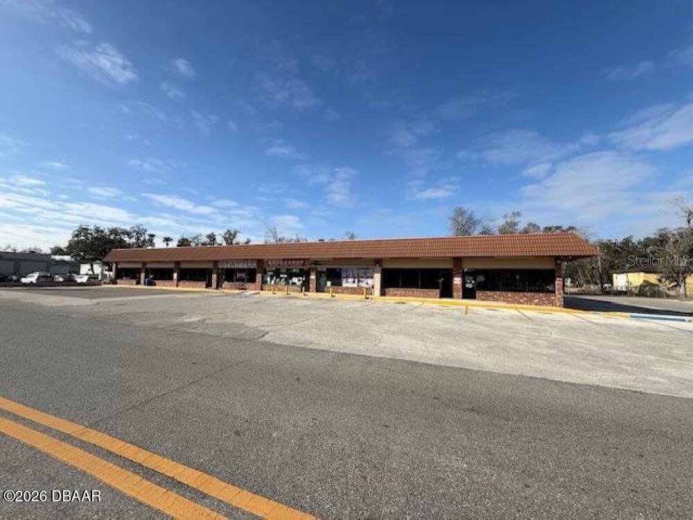A single-story commercial strip mall building with a large paved parking lot in front — 1396 N NOVA ROAD, DAYTONA BEACH, FL