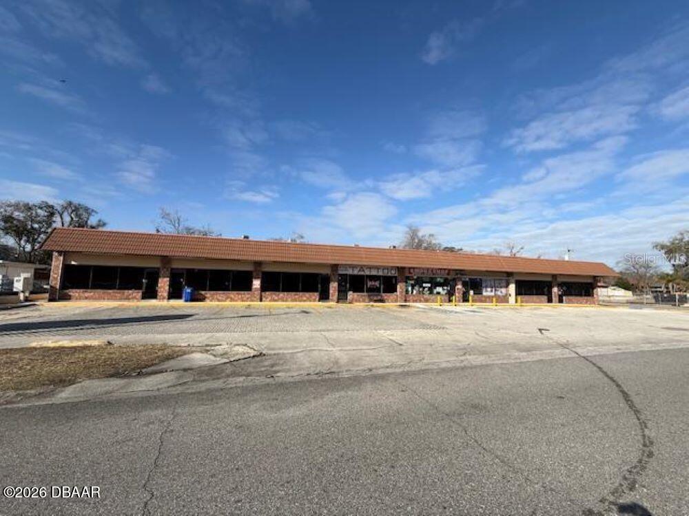 A single-story commercial strip mall building with a brown tiled roof and parking lot — 1396 N NOVA ROAD, DAYTONA BEACH, FL