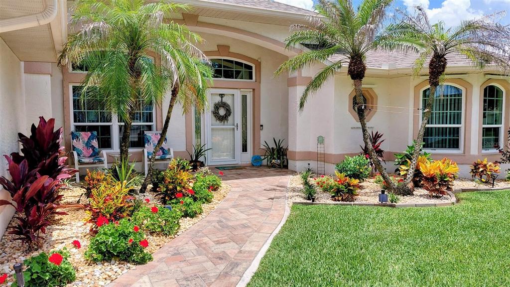 A paved walkway leads to the front entrance of a house with palm trees — 2713 TURNBULL ESTATES DRIVE, NEW SMYRNA BEACH, FL