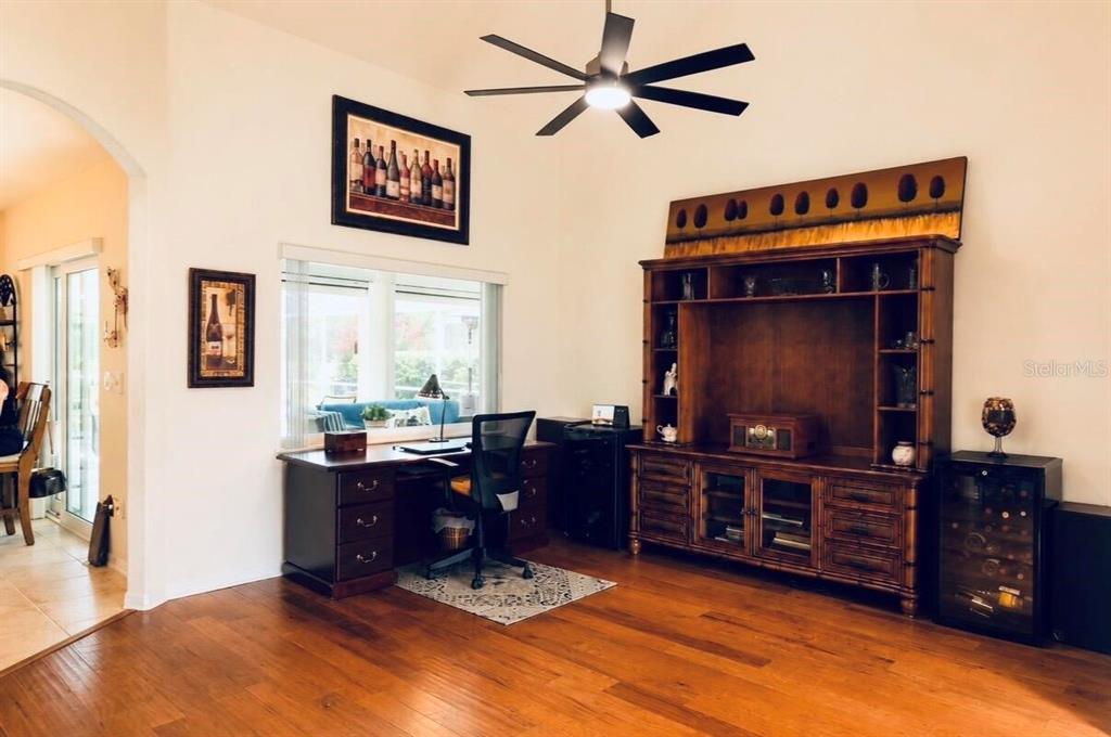 A room with hardwood floors, a large wooden entertainment center, a desk, and a ceiling fan — 2713 TURNBULL ESTATES DRIVE, NEW SMYRNA BEACH, FL