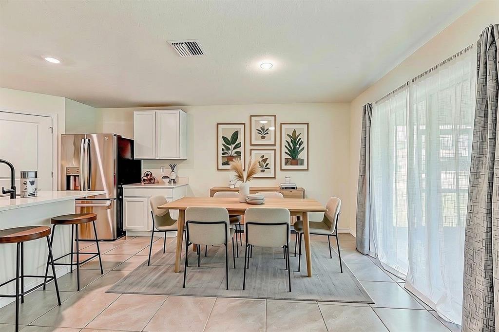 A dining area with a wooden table, chairs, and wall art sits beside a kitchen — 13419 CHIPPENDALE STREET, SPRING HILL, FL