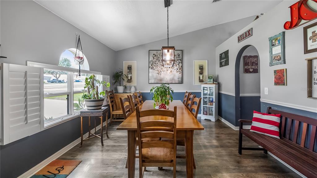 A dining room features a wooden table, chairs, a bench, and gray and blue walls — 1101 MYRTLE LAKE VIEW DRIVE, FRUITLAND PARK, FL