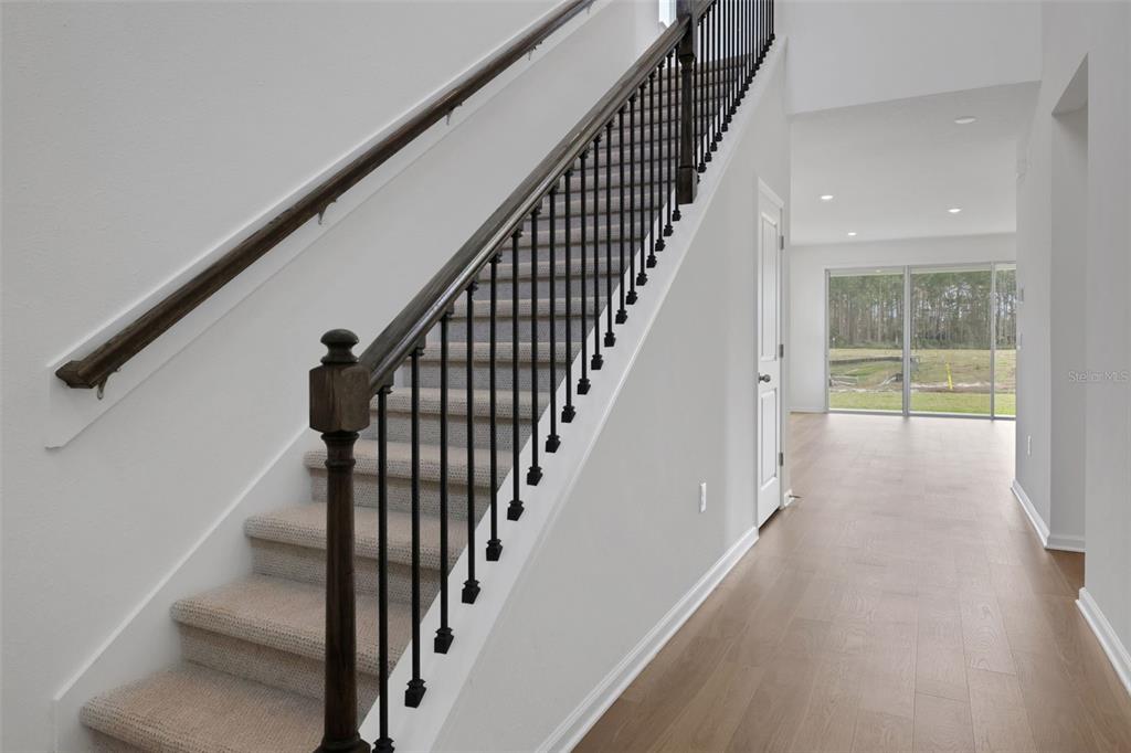 A staircase with carpeted steps and a dark wood railing leads upstairs in a hallway — 167 LAKE FRANCES DRIVE, ST AUGUSTINE, FL