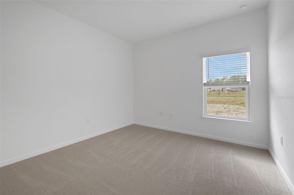 An empty bedroom features white walls, beige carpeting, and a window with horizontal blinds — 167 LAKE FRANCES DRIVE, ST AUGUSTINE, FL