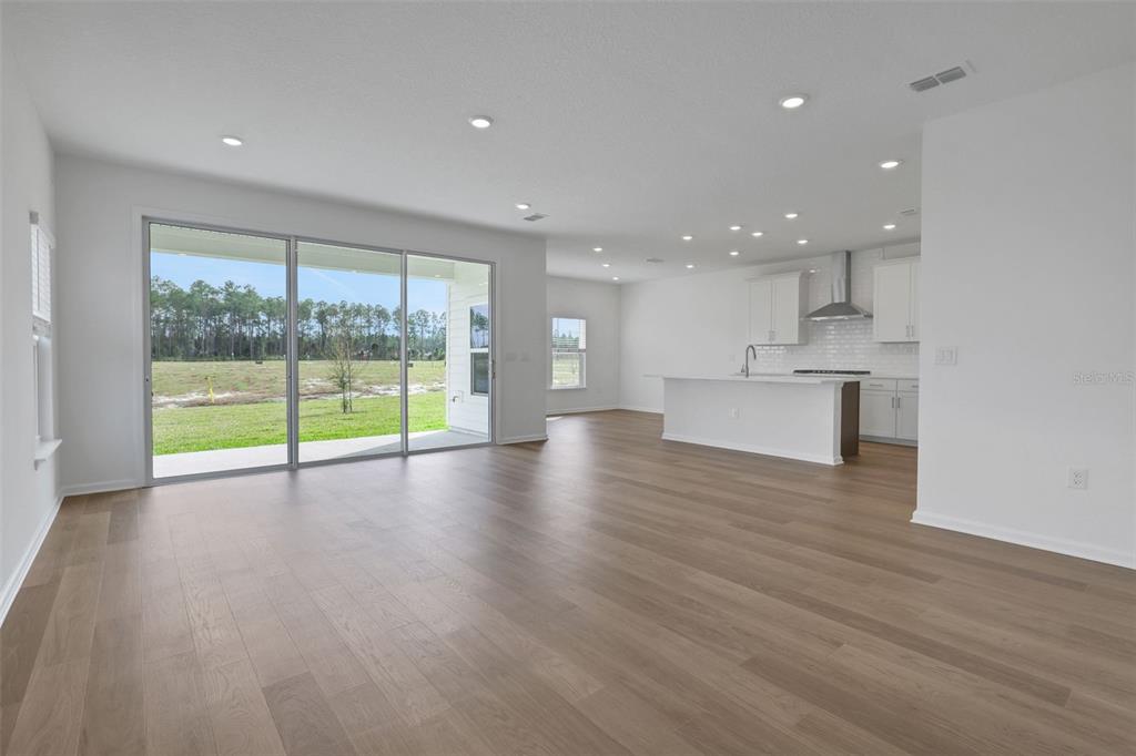 An open-concept living area with light wood floors, recessed lighting, and a modern white kitchen — 167 LAKE FRANCES DRIVE, ST AUGUSTINE, FL