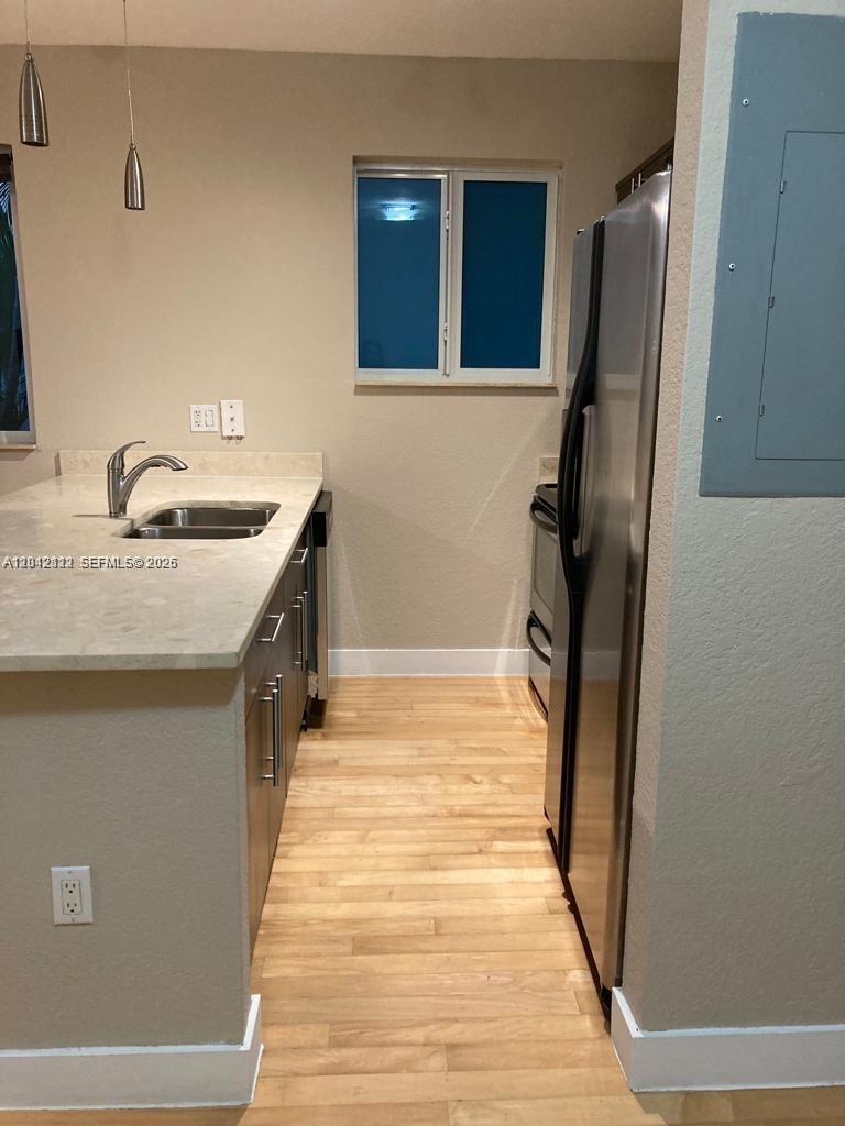 A kitchen features light wood flooring, stainless steel appliances, and a light-colored countertop — 7171 Bay Dr # 9, Miami Beach FL 33141, MIAMI BEACH, FL