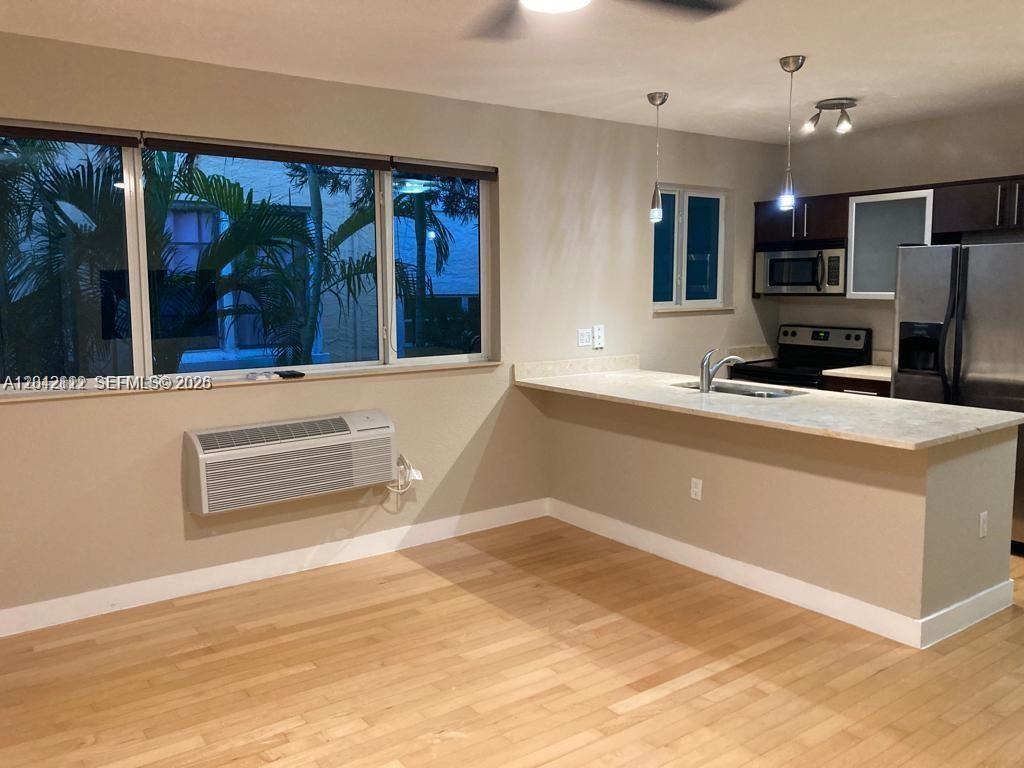 A kitchen with a breakfast bar overlooks a living area with light wood flooring — 7171 Bay Dr # 9, Miami Beach FL 33141, MIAMI BEACH, FL