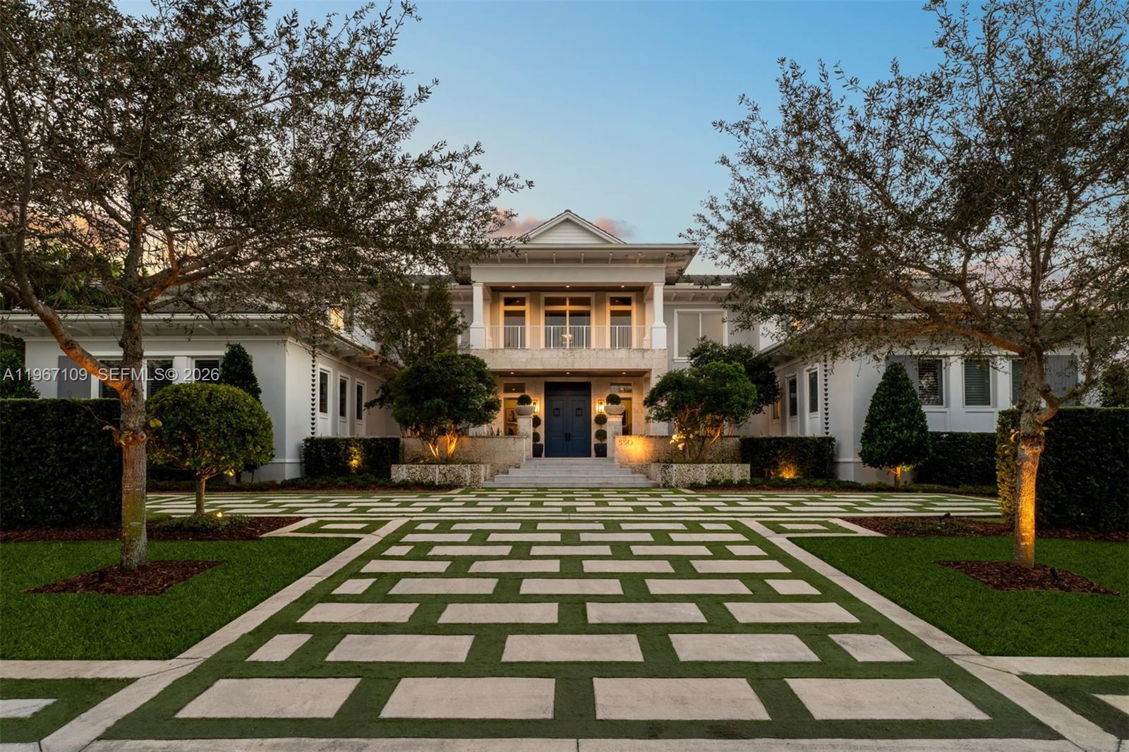A large white two-story house features a geometric paver driveway and manicured landscaping — 550 Marquesa Dr, Coral Gables FL 33156, CORAL GABLES, FL