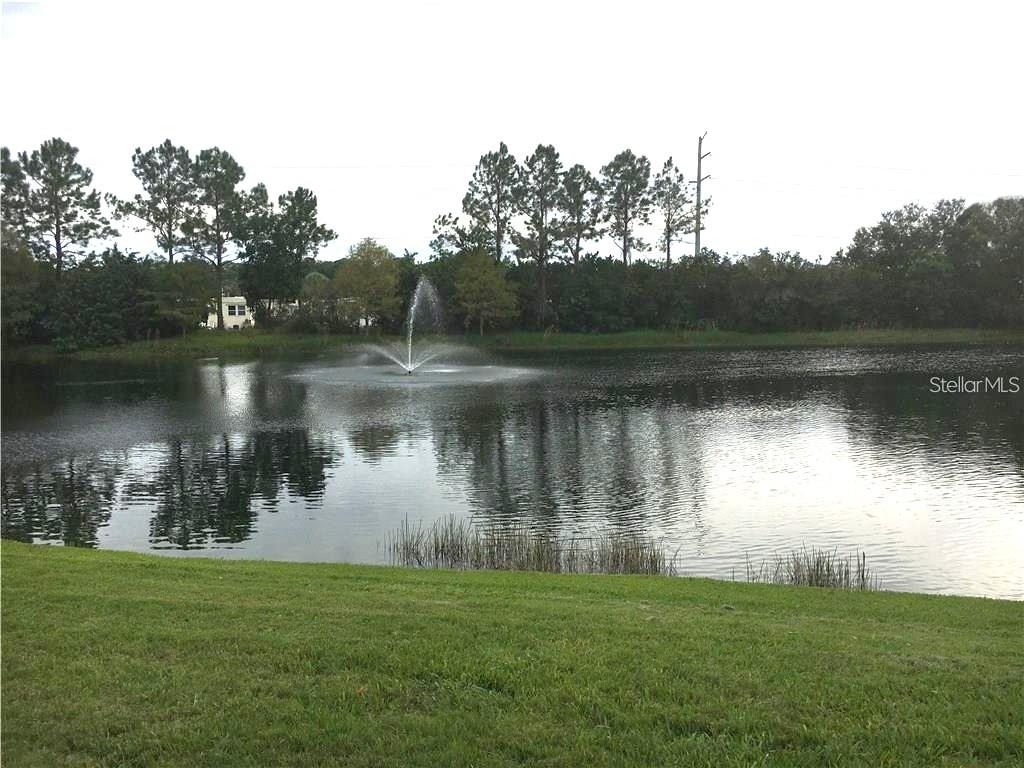 A grassy lawn overlooks a pond with a fountain and a line of trees — 4138 CENTRAL SARASOTA PARKWAY UNIT 1516, SARASOTA, FL