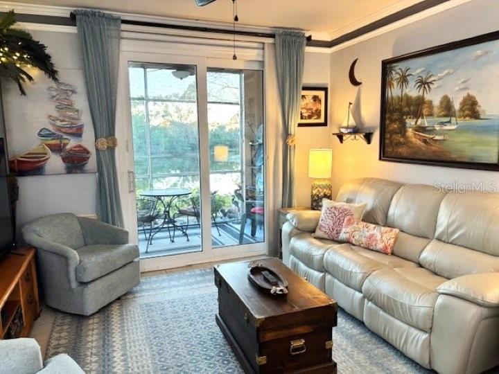 A living room features a beige leather sofa, a gray armchair, and sliding glass patio doors — 4138 CENTRAL SARASOTA PARKWAY UNIT 1516, SARASOTA, FL