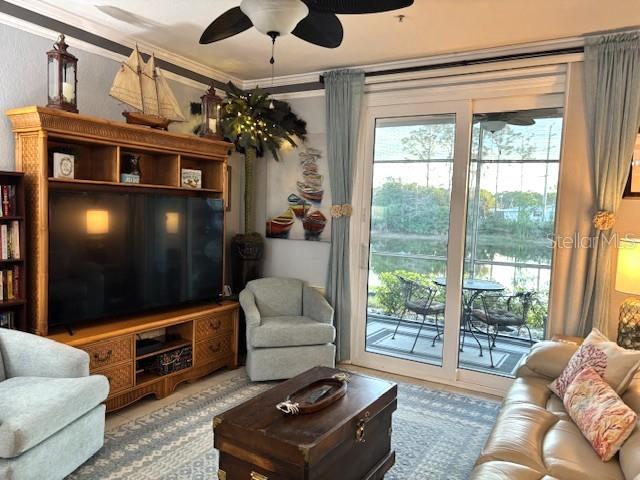A living room features a large television, wicker furniture, a ceiling fan, and sliding glass doors — 4138 CENTRAL SARASOTA PARKWAY UNIT 1516, SARASOTA, FL