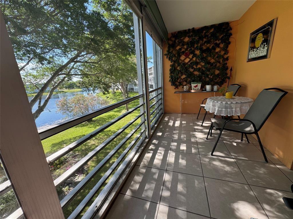A screened-in balcony with tile flooring overlooks a lake and green lawn — 3058 Cambridge C # 3058, Deerfield Beach FL 33442, DEERFIELD BEACH, FL
