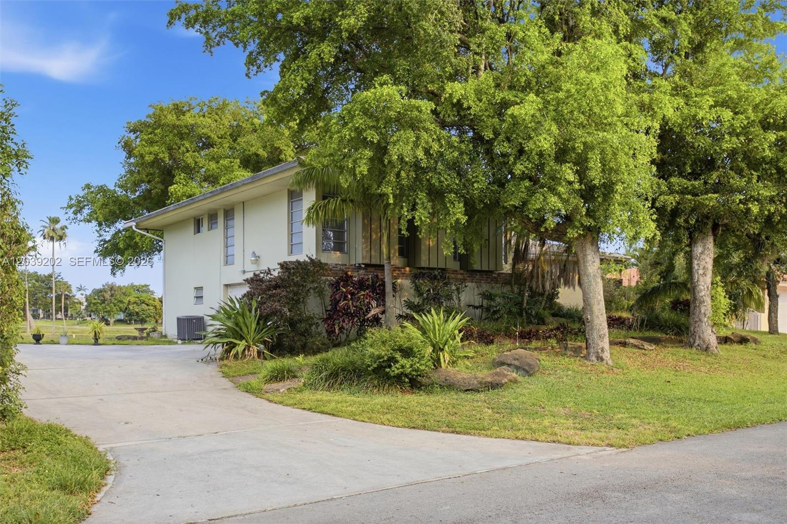 A two-story house with a concrete driveway and mature trees in the front yard — 19015 E Saint Andrews Dr, Hialeah FL 33015, HIALEAH, FL