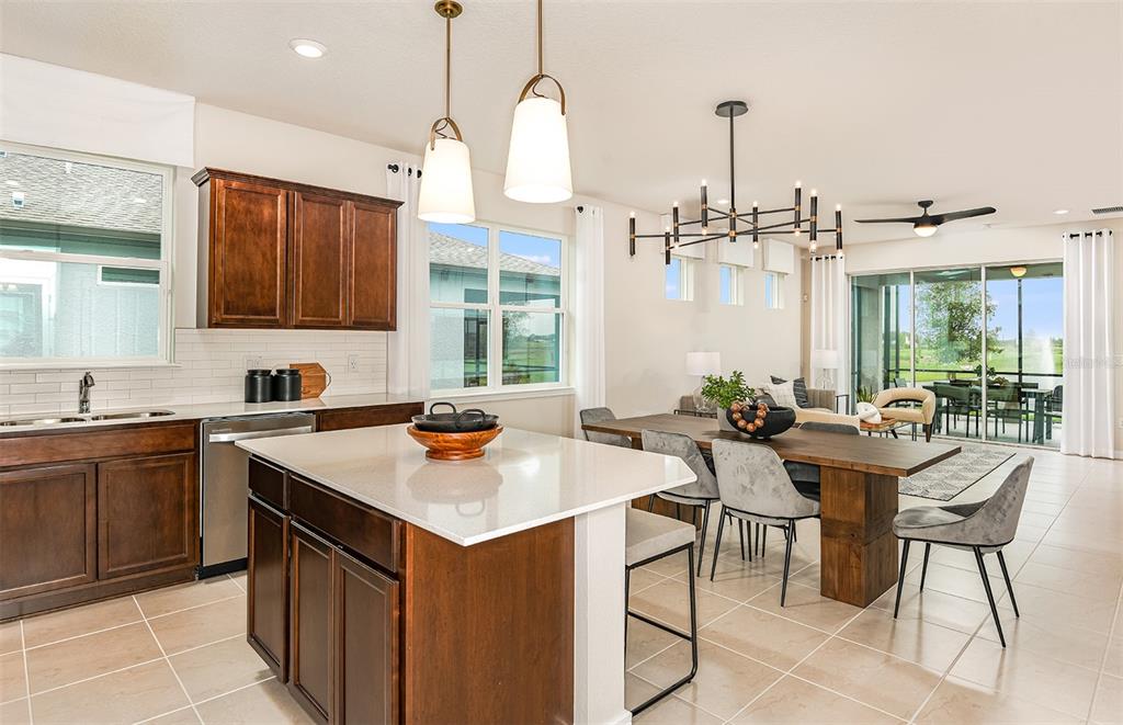 A kitchen with dark wood cabinets, a white island, and an adjacent dining area — 12509 ADOBE STREET, PARRISH, FL