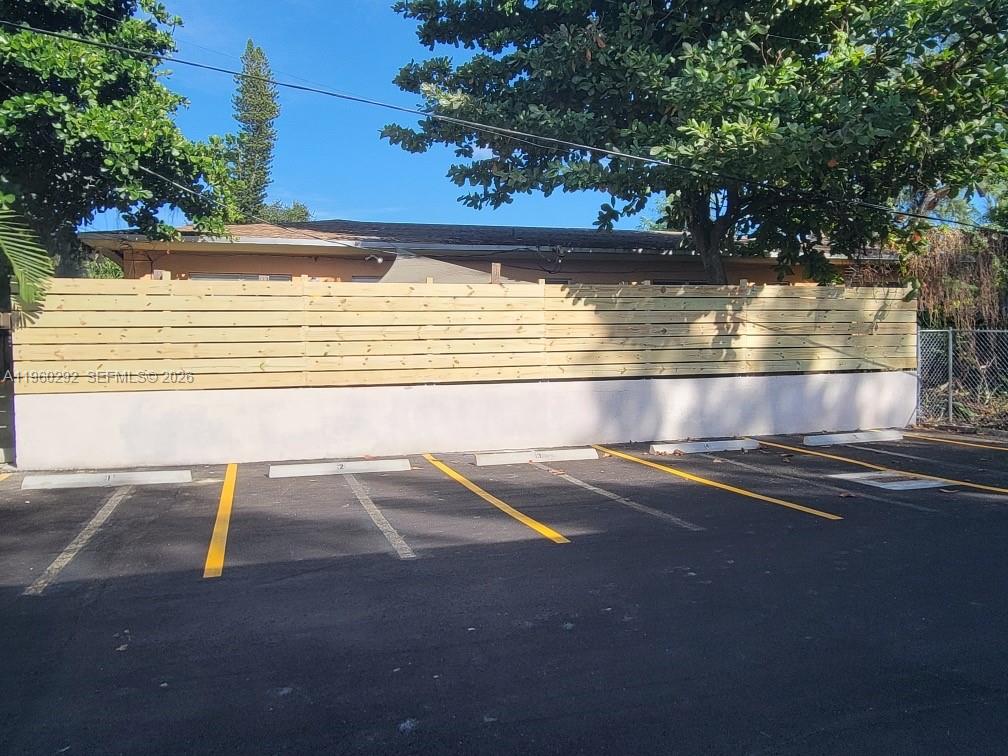A parking lot with five marked spaces sits in front of a horizontal wood fence — 7843 NE 10th Ave # 2, Miami FL 33138, MIAMI, FL