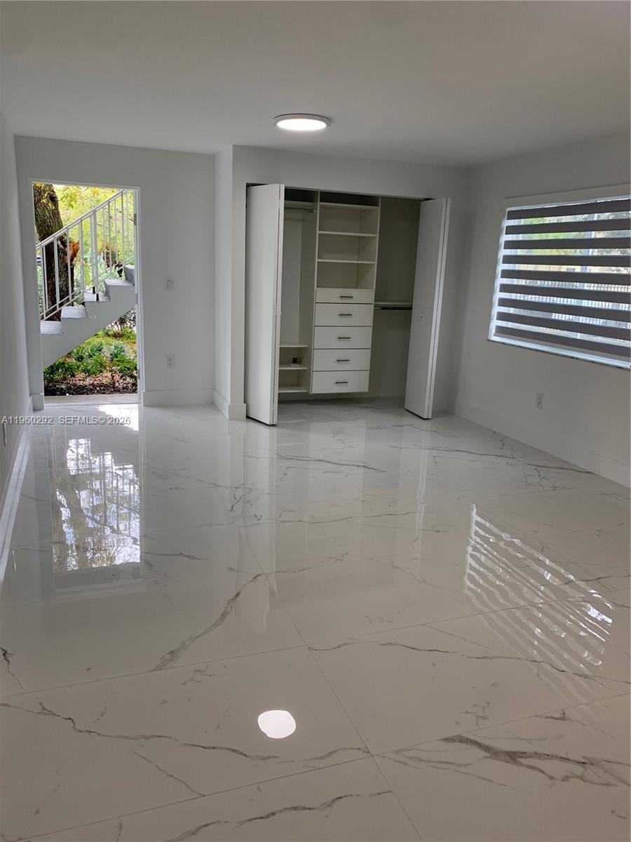 A bedroom with white marble-look tile flooring, a built-in closet, and an exterior door — 7843 NE 10th Ave # 2, Miami FL 33138, MIAMI, FL