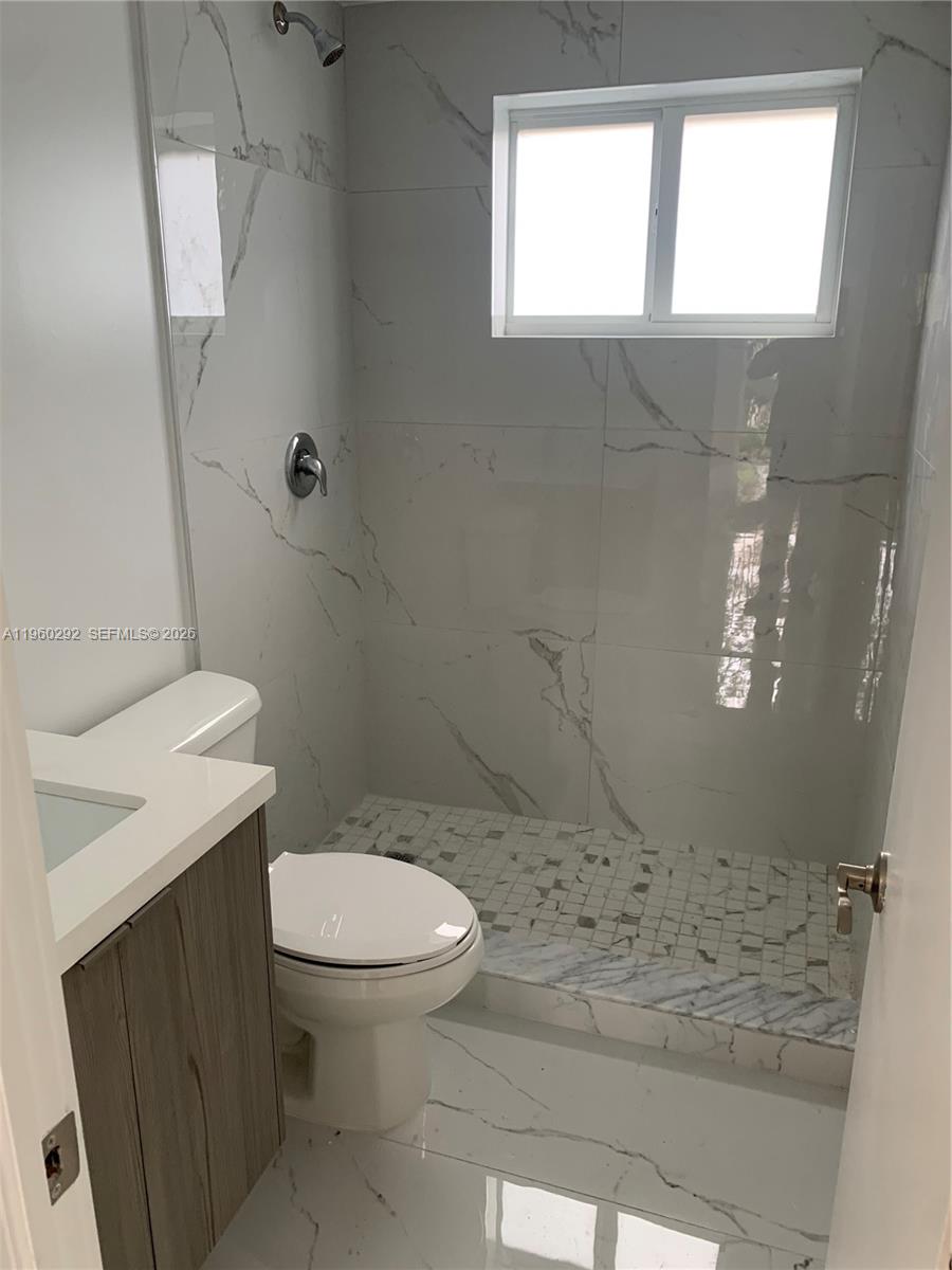 A small bathroom features a walk-in shower with white marble-look tile and a vanity — 7843 NE 10th Ave # 2, Miami FL 33138, MIAMI, FL
