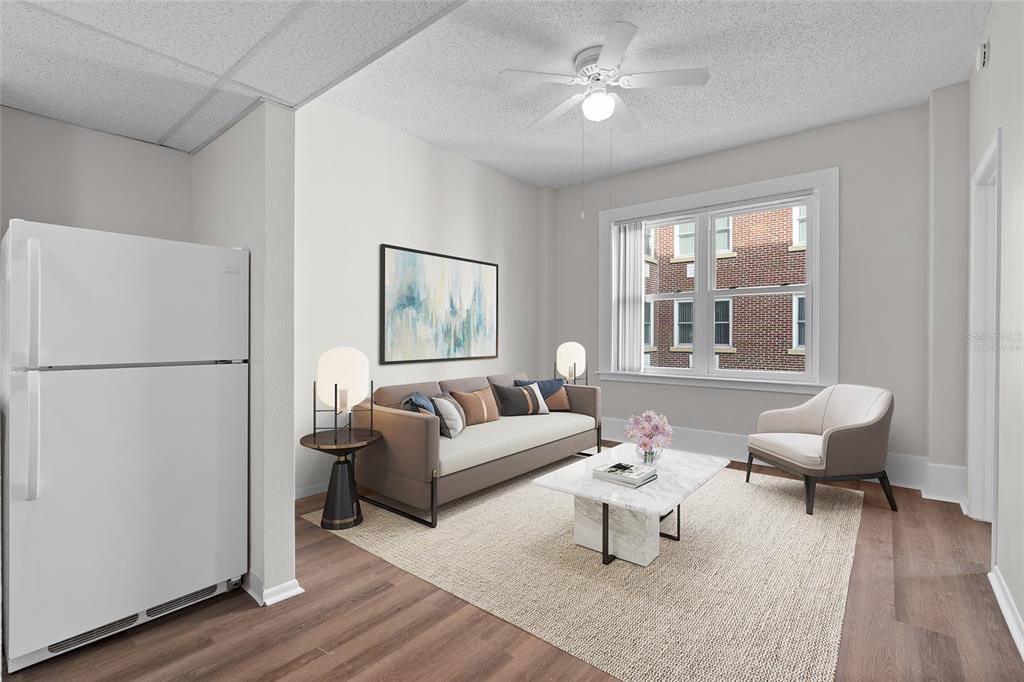 This is a digitally staged living room featuring a sofa, armchair, and a white refrigerator — 411 1ST AVENUE N UNIT 702, ST PETERSBURG, FL