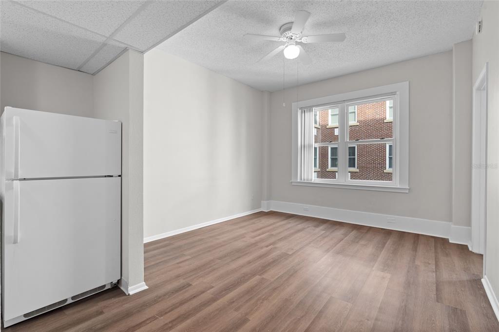 A room with light-colored walls, wood-look flooring, a ceiling fan, and a white refrigerator — 411 1ST AVENUE N UNIT 702, ST PETERSBURG, FL