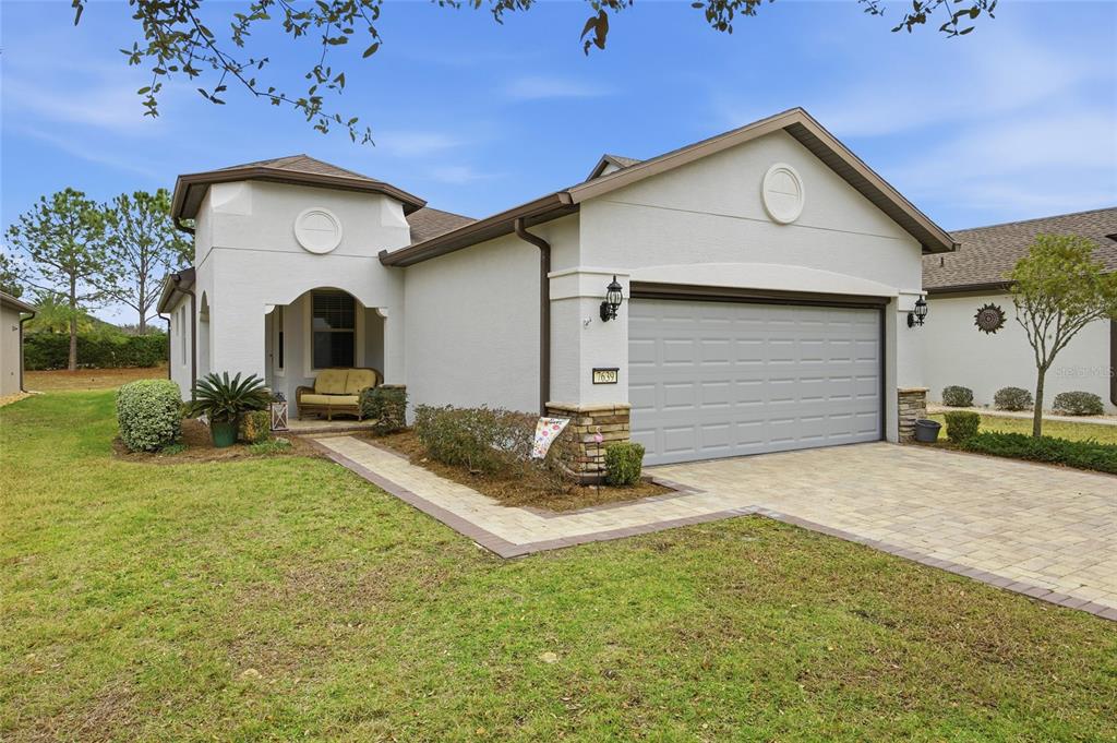 A single-story house with a beige stucco exterior, a two-car garage, and a paved walkway — 7639 SW 94TH CIRCLE, OCALA, FL