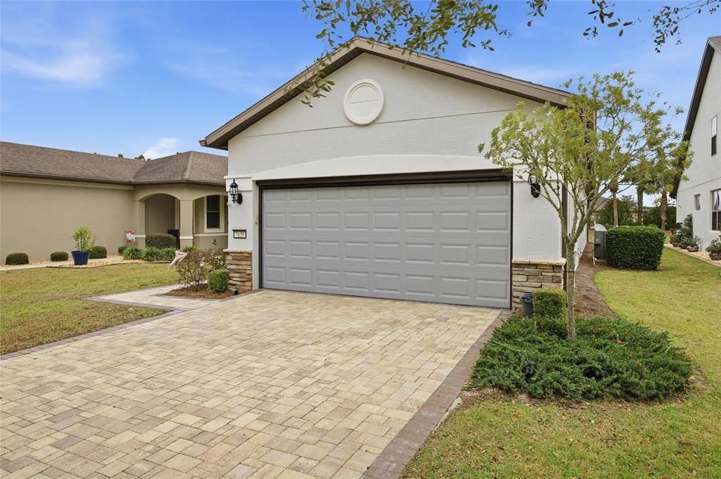 A single-story house with a gray garage door, stone accents, and a paved driveway — 7639 SW 94TH CIRCLE, OCALA, FL
