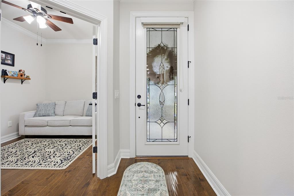 An entryway with hardwood floors leads to a living room featuring a white sofa — 7639 SW 94TH CIRCLE, OCALA, FL