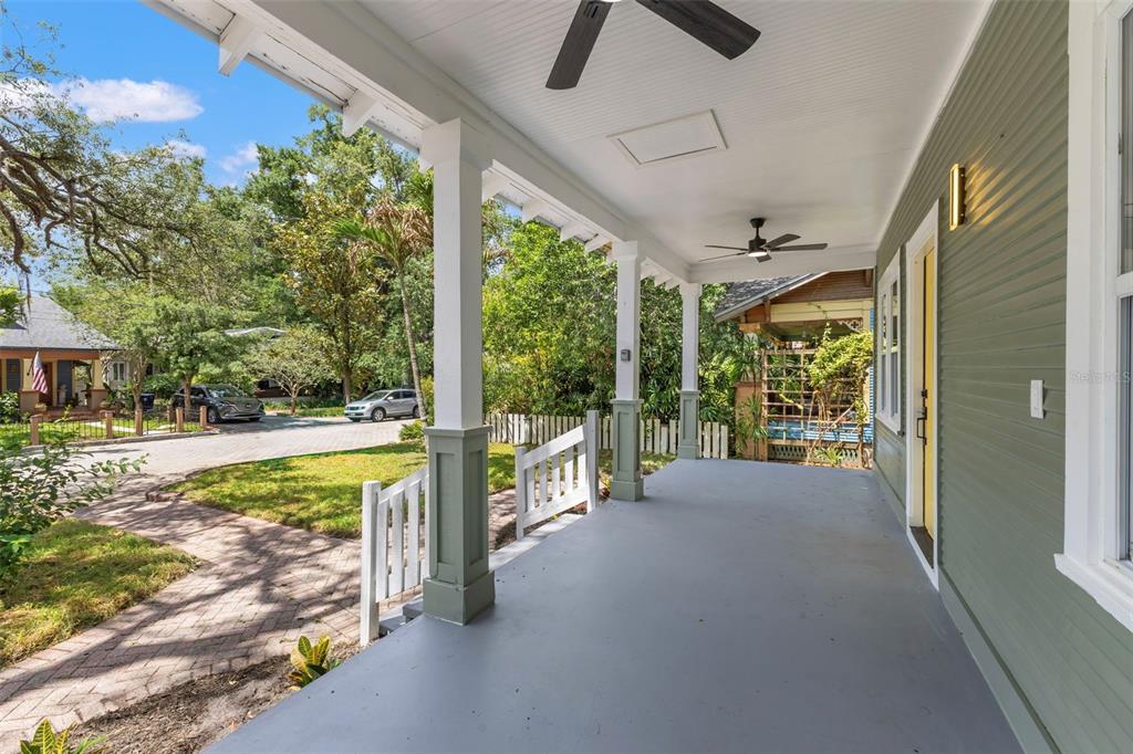 A covered front porch with gray flooring, white columns, and green siding on a sunny day — 604 E LAMBRIGHT STREET, TAMPA, FL
