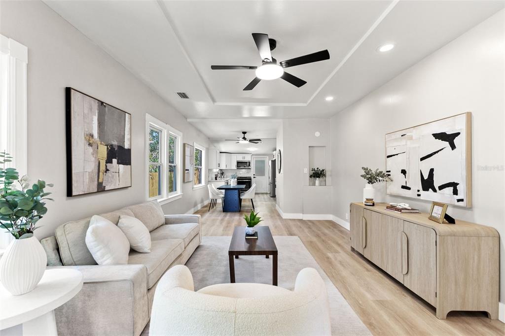 A bright living room features light wood floors, a neutral sofa, and an open kitchen — 604 E LAMBRIGHT STREET, TAMPA, FL
