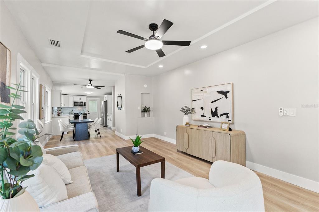 A bright living room with light wood floors, a ceiling fan, and an open kitchen — 604 E LAMBRIGHT STREET, TAMPA, FL