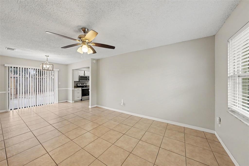 A dining area with beige tile floors, a ceiling fan, and a view of the kitchen — 10410 N 27TH STREET, TAMPA, FL