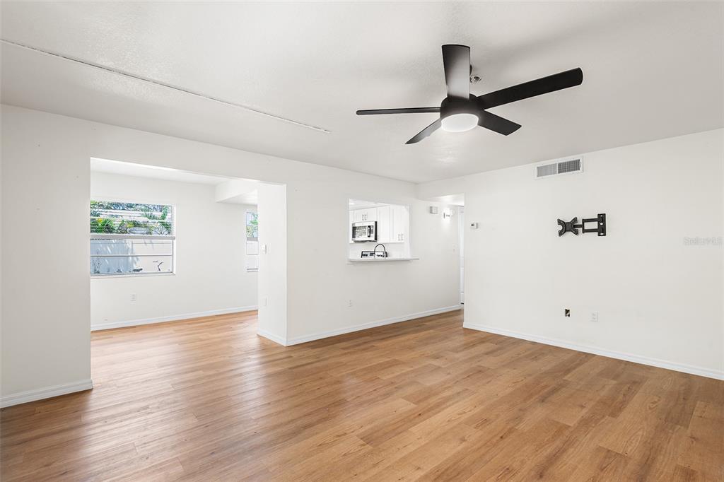An empty living room with light wood-look flooring, white walls, and a ceiling fan — 2865 51ST STREET S UNIT 5, GULFPORT, FL
