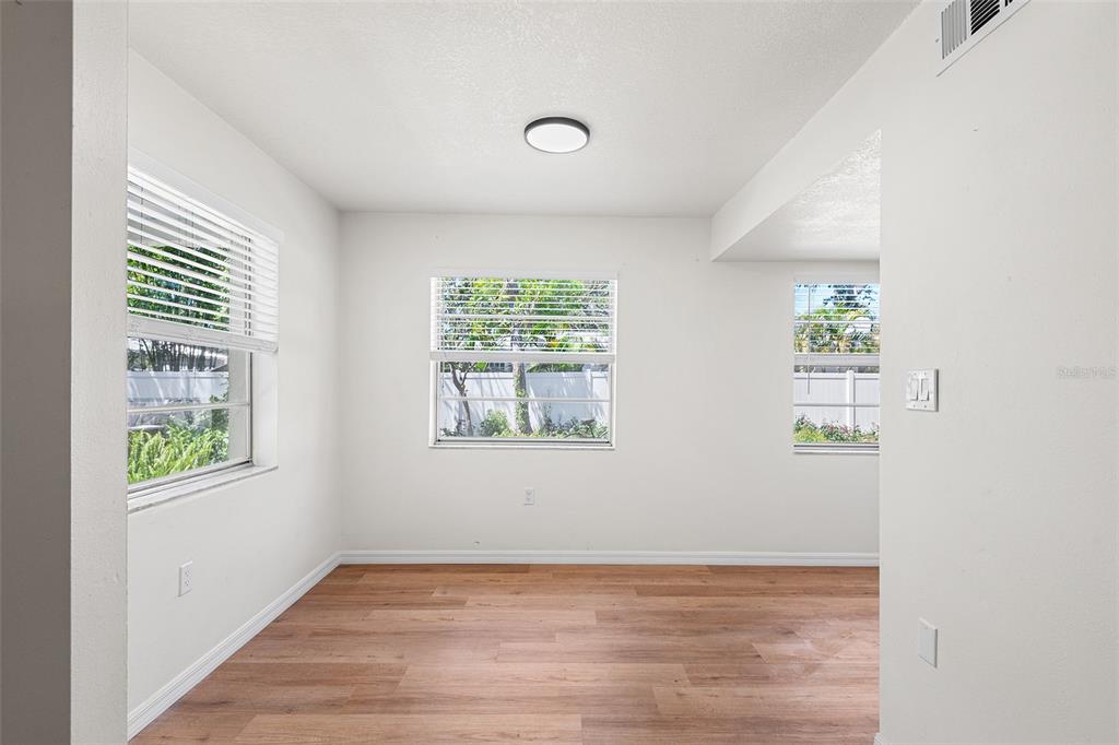 An empty room with white walls, wood-look flooring, and three windows with white blinds — 2865 51ST STREET S UNIT 5, GULFPORT, FL