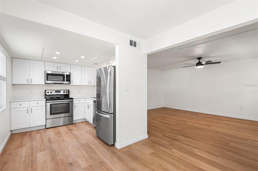 A kitchen with white cabinets and stainless steel appliances opens into a living area — 2865 51ST STREET S UNIT 5, GULFPORT, FL