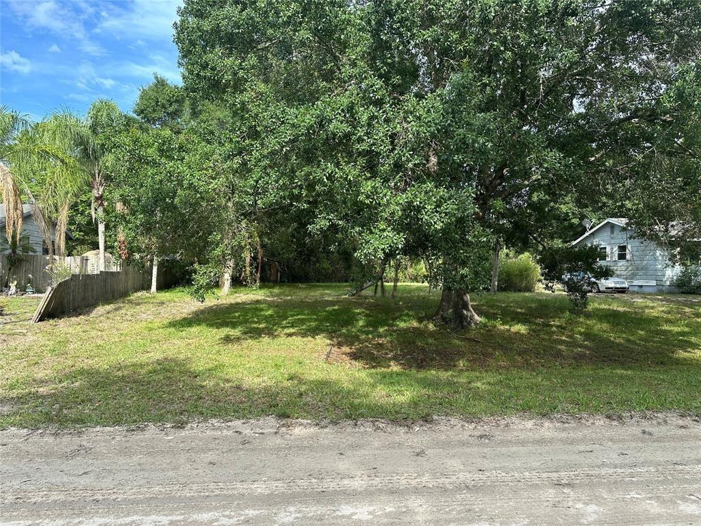 A grassy, tree-covered vacant lot sits beside a house along a dirt road — 8922 102nd Avenue, Vero Beach FL 32967, VERO BEACH, FL