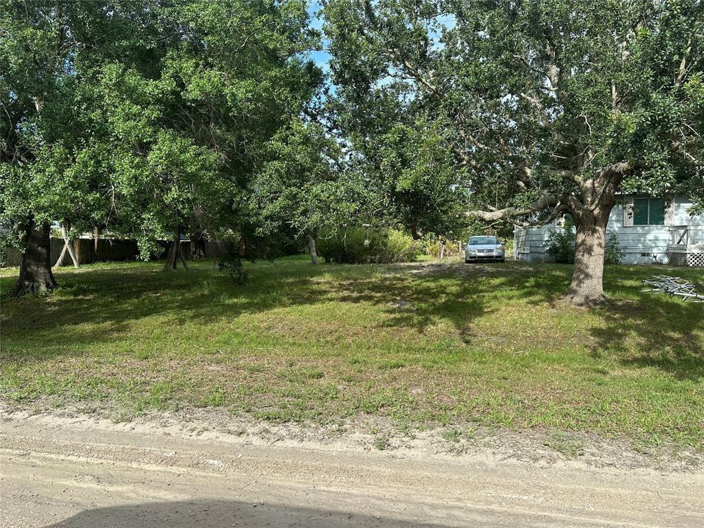A grassy, tree-lined vacant lot sits next to a small house with a parked car — 8922 102nd Avenue, Vero Beach FL 32967, VERO BEACH, FL