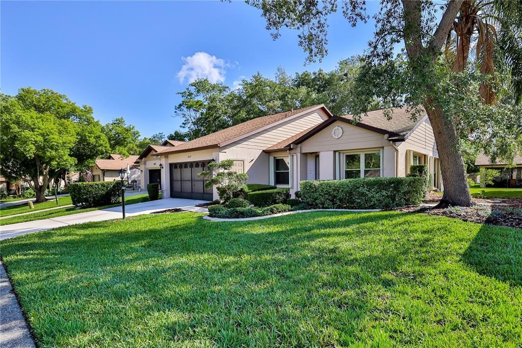 A single-story suburban house with a tan exterior, a two-car garage, and a manicured lawn — 2662 APPLELEAF COURT, SPRING HILL, FL