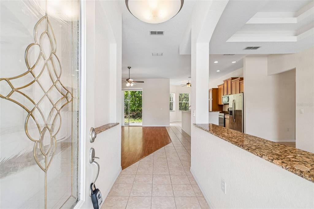 An entryway with tile flooring leads into a living area with wood floors and kitchen — 37 GREENPARK BOULEVARD, HOMOSASSA, FL