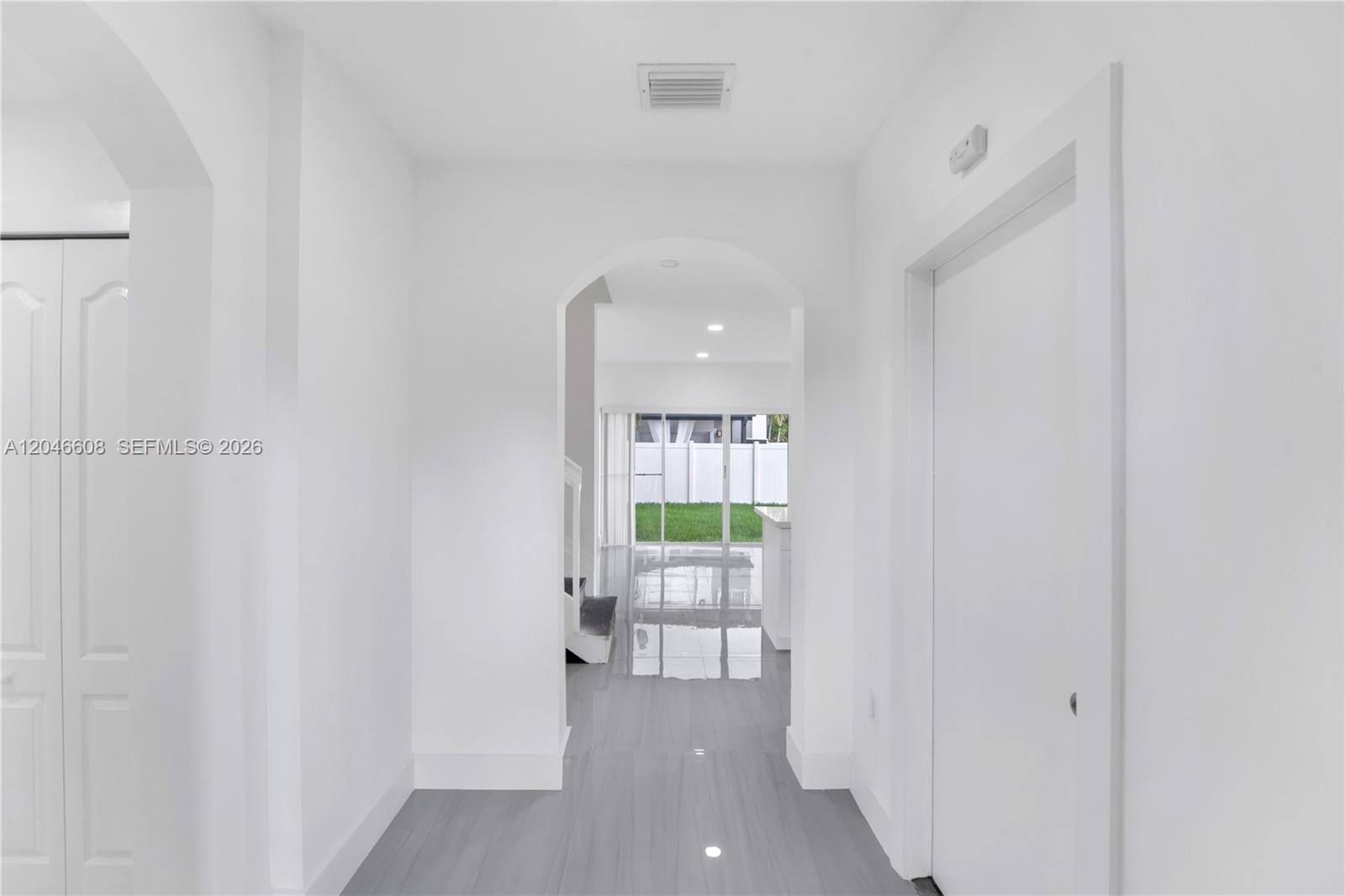 A bright hallway with white walls and gray flooring leads through an arched doorway — 2802 SW 128th Way # B, Miramar FL 33027, MIRAMAR, FL