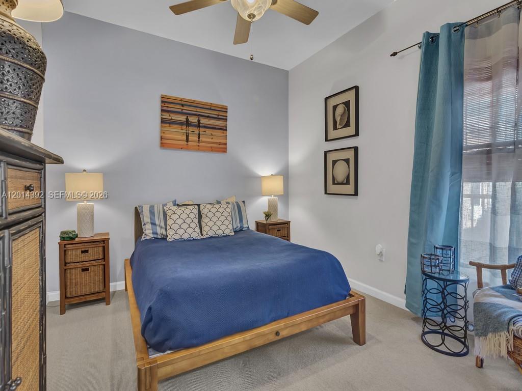 A bedroom features a wooden bed frame, blue bedding, two nightstands, and wall art — 5035 Fairways Cir # 305, Vero Beach FL 32967, VERO BEACH, FL
