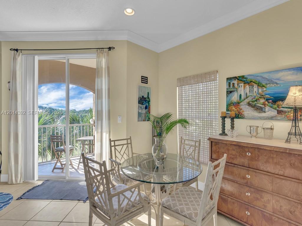 A dining area features a glass table, four chairs, a wooden dresser, and a balcony — 5035 Fairways Cir # 305, Vero Beach FL 32967, VERO BEACH, FL