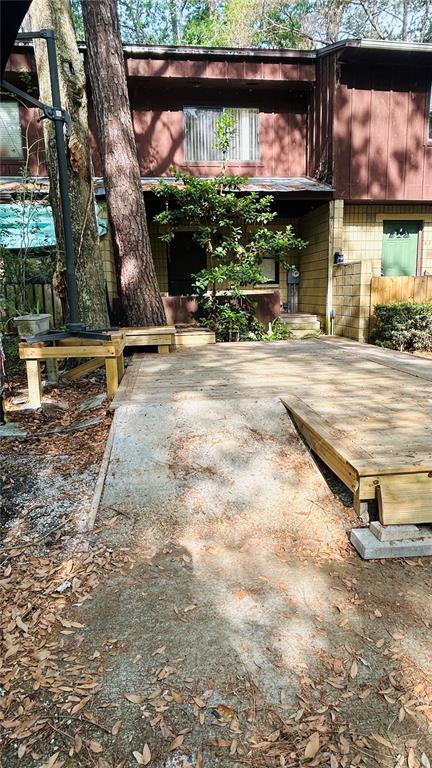 A wooden deck with a concrete ramp leads to the entrance of a brown house — 4328 SW 69TH TERRACE, GAINESVILLE, FL