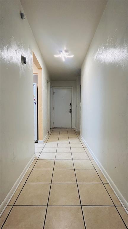 A narrow hallway with light-colored tile flooring leads to a white front door — 4328 SW 69TH TERRACE, GAINESVILLE, FL