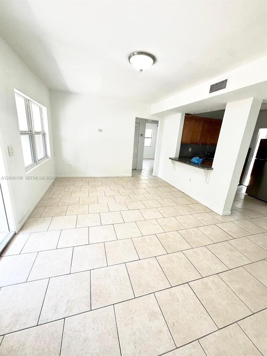 This room features light-colored tile flooring, white walls, and an open pass-through to the kitchen — MIAMI BEACH, FL