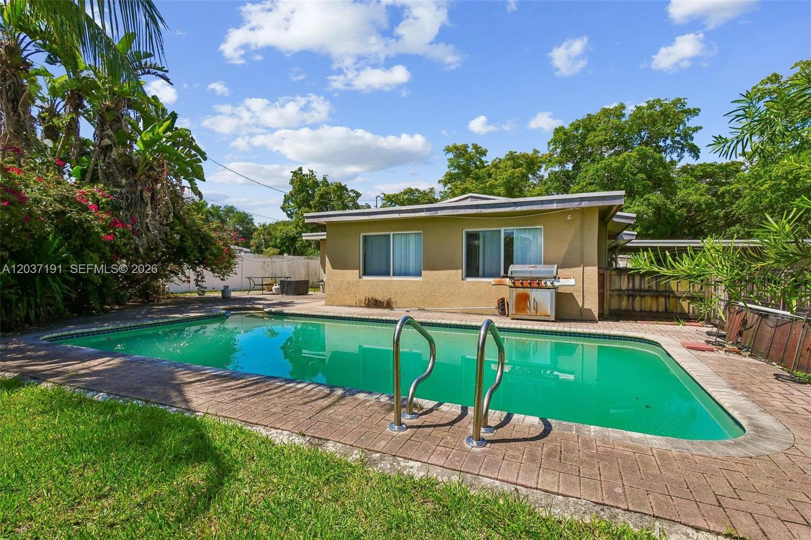 A backyard features a rectangular swimming pool with a brick deck and a small house — 401 S 57th Ter, Hollywood FL 33023, HOLLYWOOD, FL