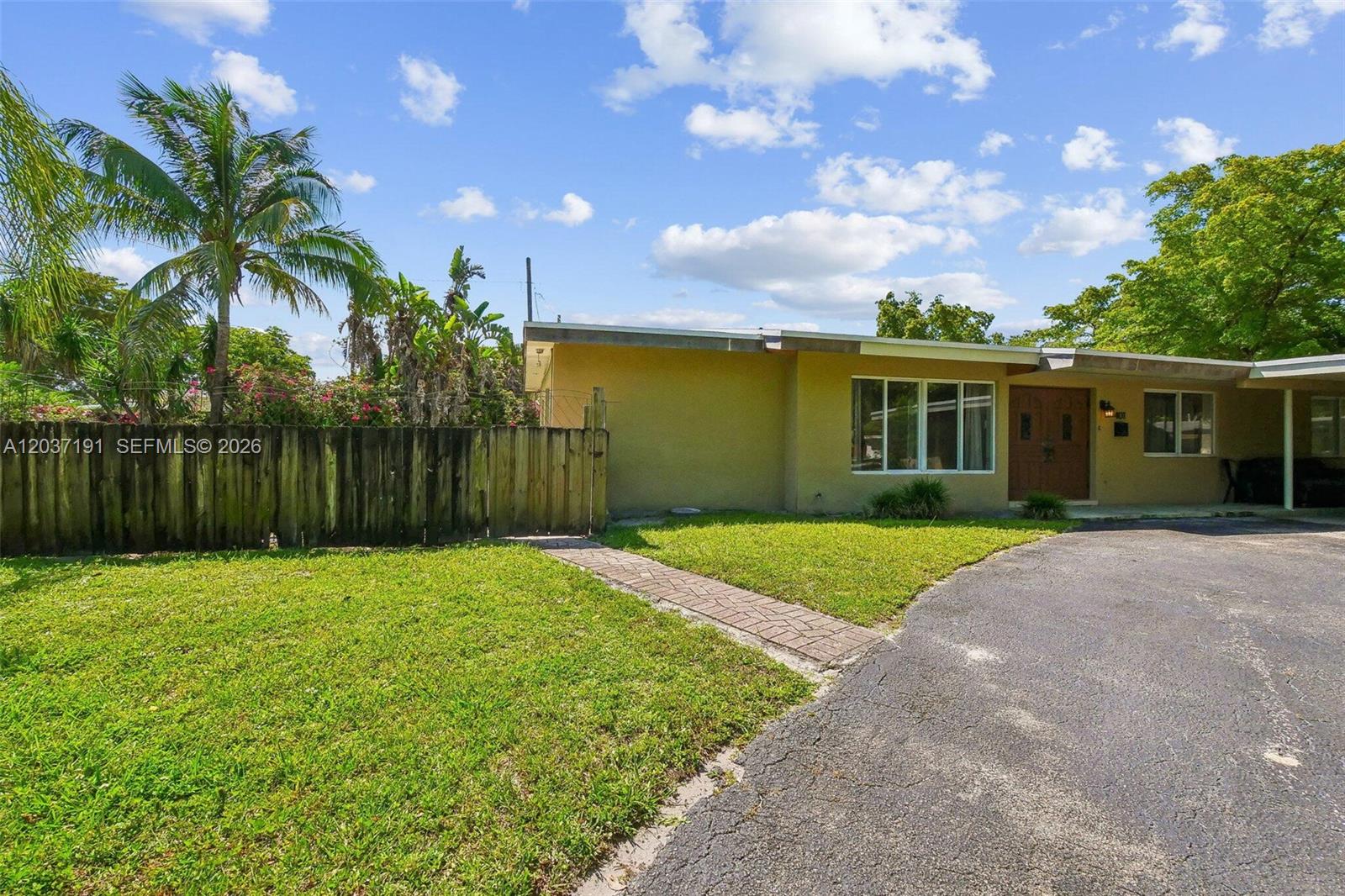 A single-story yellow house features a paved walkway, a wooden fence, and a driveway — 401 S 57th Ter, Hollywood FL 33023, HOLLYWOOD, FL