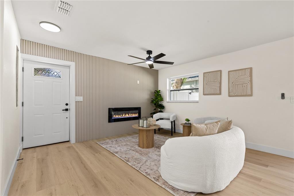 A living room features light wood flooring, a slatted accent wall, and a modern fireplace — 815 W MINNEHAHA STREET, TAMPA, FL