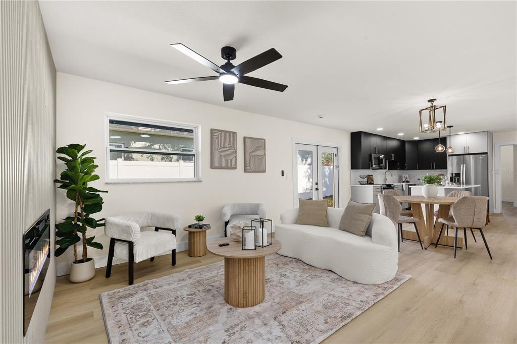 An open-concept living and dining area features light wood flooring, a modern kitchen, and furniture — 815 W MINNEHAHA STREET, TAMPA, FL