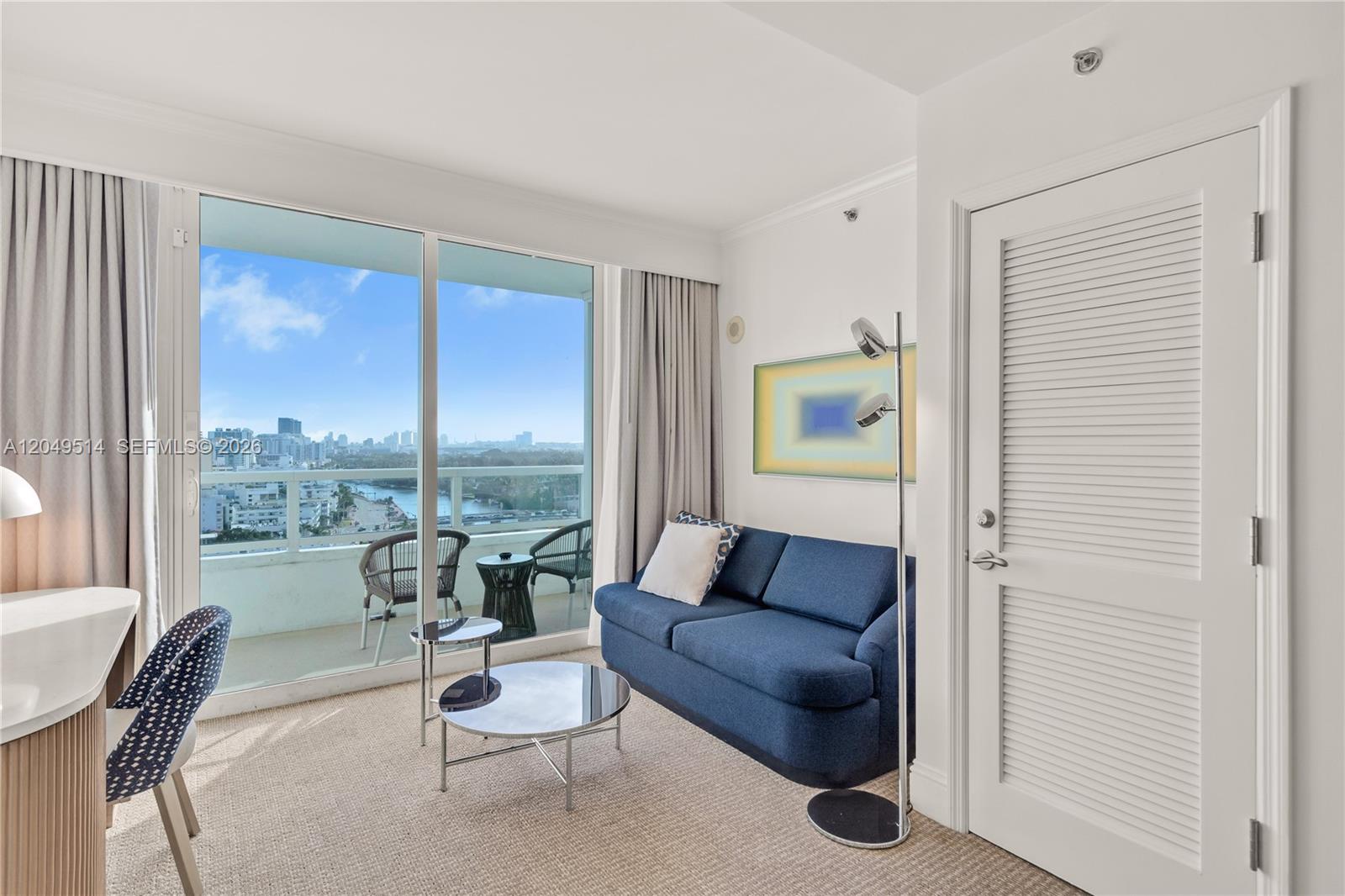A living area features a blue sofa, a glass coffee table, and a balcony view — 4401 Collins Ave # 1508, Miami Beach FL 33140, MIAMI BEACH, FL
