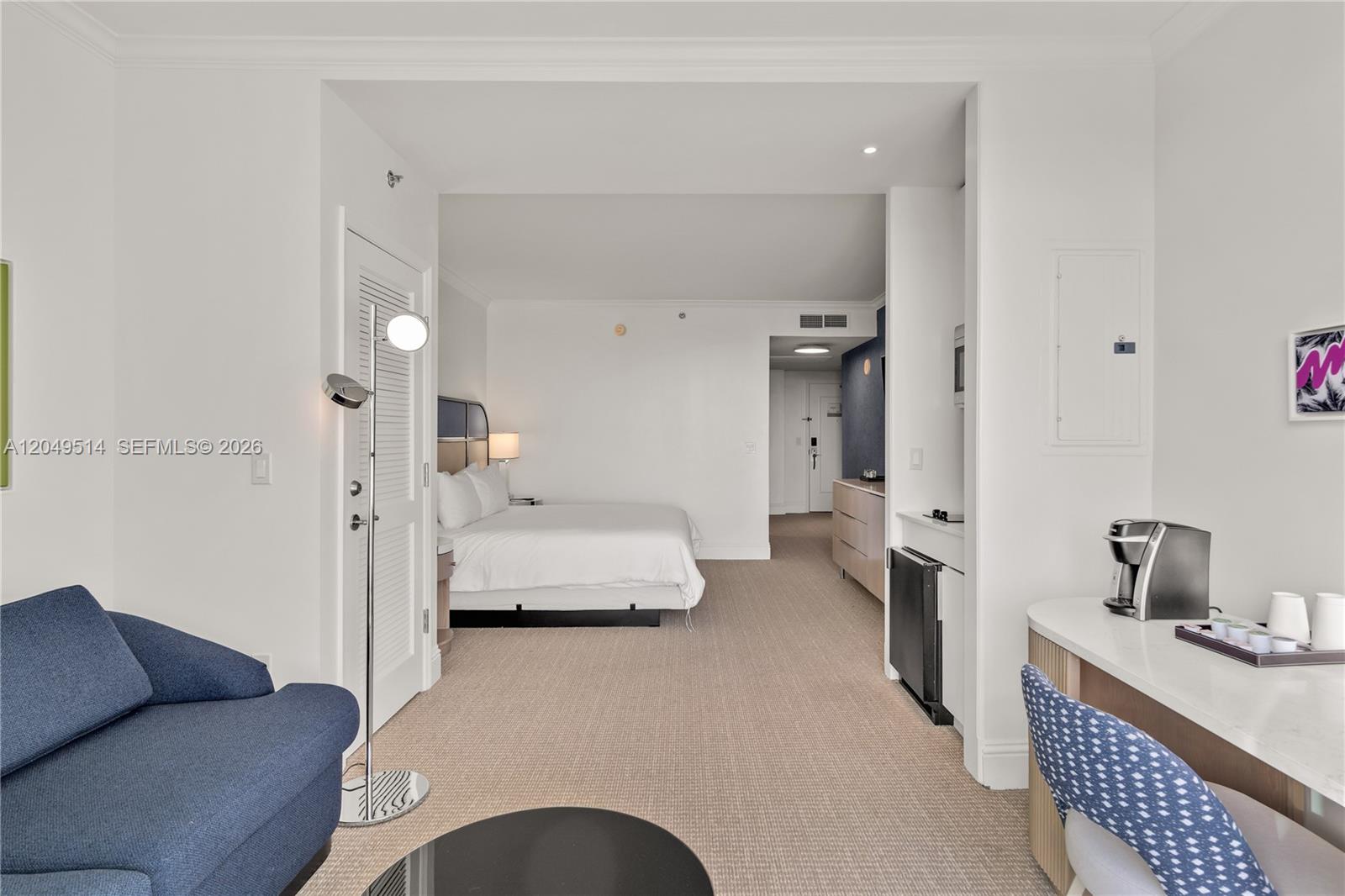 A hotel room features a bed, a blue armchair, and a desk with a coffee maker — 4401 Collins Ave # 1508, Miami Beach FL 33140, MIAMI BEACH, FL