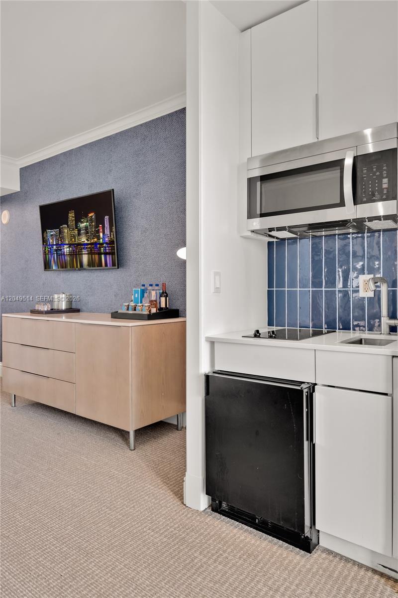 A kitchenette with a microwave and mini-fridge sits beside a room with a dresser — 4401 Collins Ave # 1508, Miami Beach FL 33140, MIAMI BEACH, FL
